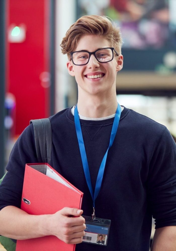 portrait-of-smiling-male-college-student-in-busy-communal-campus-building-e1701494224421.jpg